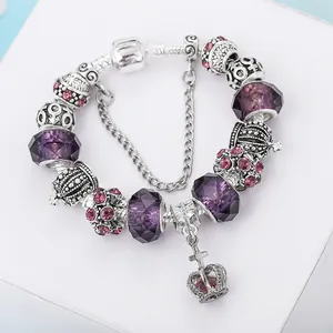 Detailed view of crown pendant charms and purple beads on a silver snake chain bracelet