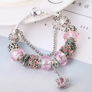 Detailed close-up of pink glass beads and crown charm on a silver snake chain bracelet