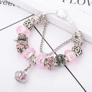 Macro detail of silver snake chain bracelet with pink crystal beads and crown pendant
