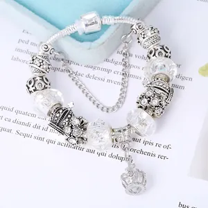Macro view of silver snake chain bracelet featuring crown charms and zircon beads