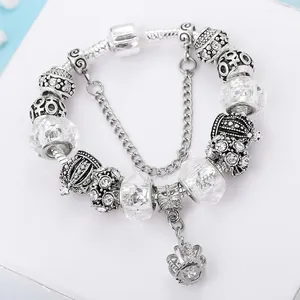 Detailed close-up of a silver crown charm bracelet with crystal beads and a safety chain