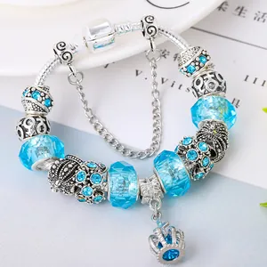 Detailed macro view of silver charm bracelet with crown pendant and blue glass beads