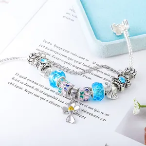 Detail van zilveren slangarmband met blauwe kralen en hanger van klavertje bloem