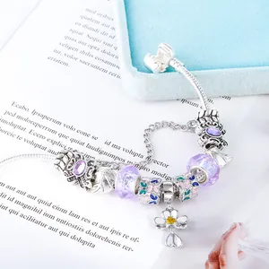 Detail van kralenarmband met paarse glazen kralen en bedeltjes met bloemen van emaille