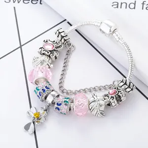 Detail van de slangenarmband met roze glazen kralen en bedeltjes van bloemen