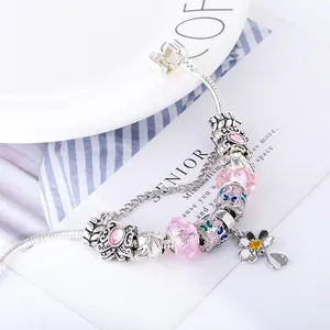 Detail van een DIY kralenarmband met roze kristallen kralen en bloemen hanger