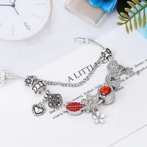 Pulsera de plata con dijes de corazón y piedras rojas sobre fondo floral