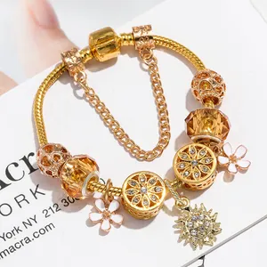 Golden snake chain bracelet with amber crystals and sunflower charms on a white card