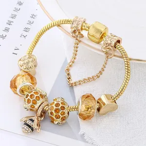 Vue macro du bracelet abeille doré avec perles en cristal ambré et détails alvéolés
