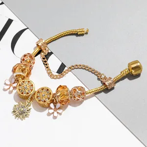 Golden snake chain charm bracelet with sun pendant, white flower, and glass beads
