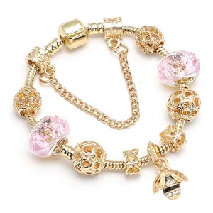 Gouden bijen-bedelarmband met roze kristallen kralen en veiligheidsketting op wit