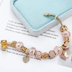 Bracciale con perline rosa sfaccettate e ciondolo a cuore dorato su scatola blu