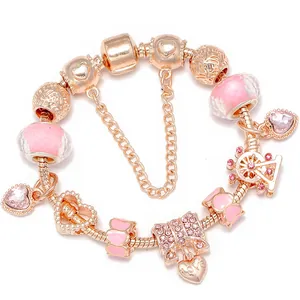 Bracelet maille serpent or rose avec perles en verre rose et breloques cœur sur fond blanc