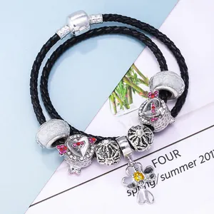 Double-layered black braided leather charm bracelet with floral and heart pendants