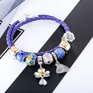 Purple braided leather charm bracelet with floral pendants and butterfly beads
