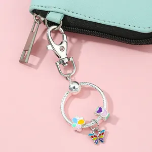 Detail van een zilveren sleutelhanger met kleurrijke emaille bloem en vlinder charms
