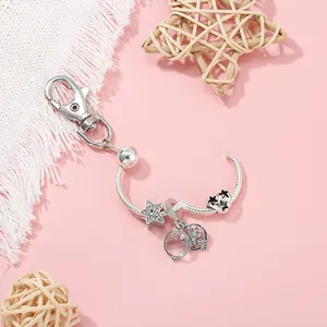 Détails du porte-clés en métal argenté avec pendentifs étoiles scintillants sur fond rose