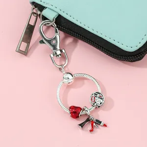Detailed shot of red strawberry and lipstick charms on a silver snake chain keychain