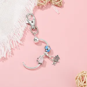 Detailed shot of travel-themed keychain with globe, plane, and suitcase charms on pink background