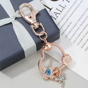 Detailed view of rose gold DIY keychain with butterfly and sun pendants on a gift box