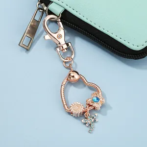 Rose gold heart keychain with daisy and blue dragonfly charms on mint leather purse
