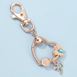 Detail of rose gold keychain with dragonfly charm and blue gemstone beads on snake chain