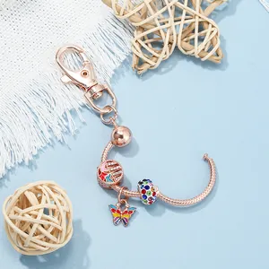 Rose gold keychain detail with colorful butterfly charm and crystal beads on snake chain