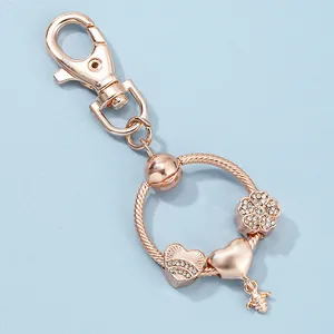 Dettaglio portachiavi in oro rosa con ciondoli a fiore e pendente a forma di ape
