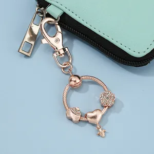 Dettaglio di ciondoli a ape e fiore in oro rosa su un anello portachiavi con moschettone