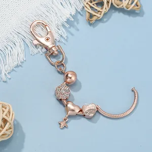 Dettaglio del portachiavi in oro rosa con ciondoli a fiore, cuore, ape e moschettone
