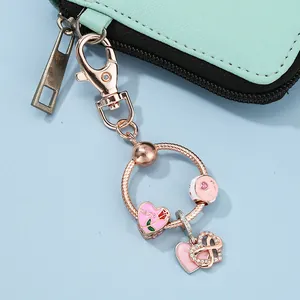 Macro detail of rose gold MOM keychain with heart charms on mint green zipper bag