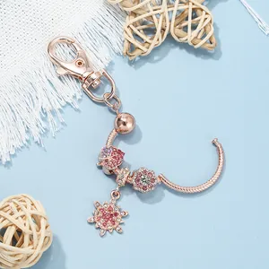 Macro detail of rose gold keychain with sparkling pink leaf and snowflake charms