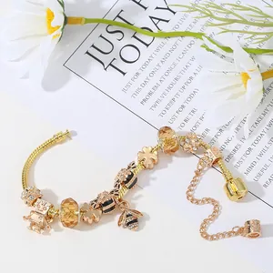Golden snake chain bracelet with bee and robot charms plus orange glass beads