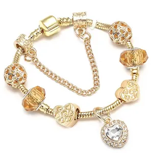 Bracelet à breloques doré avec pendentif cœur et perles ambrées sur fond blanc