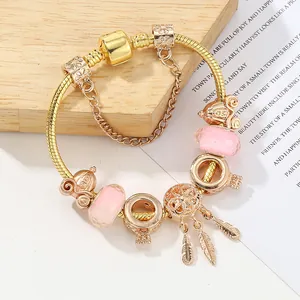 Bracciale dorato con perline di vetro rosa e ciondolo a piuma acchiappasogni elegante