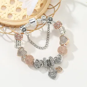 Silbernes Schlangenarmband mit Roségold-Perlen und Mamma-Herzanhängern auf weißem Tisch