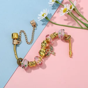 Bracciale a serpente dorato con perline di vetro floreali rosa e ciondolo chiave ala