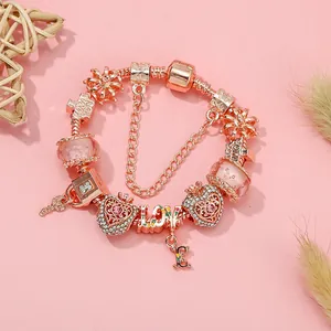 Bracciale di perline oro rosa con ciondoli a cuore e cristalli rosa su fondo rosa