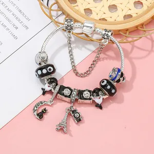 Pulsera de plata con dijes de Torre Eiffel y delfín sobre un fondo de color rosa
