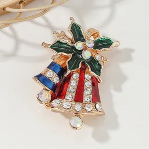 Christmas bell brooch with green holly leaves and colorful rhinestones on marble