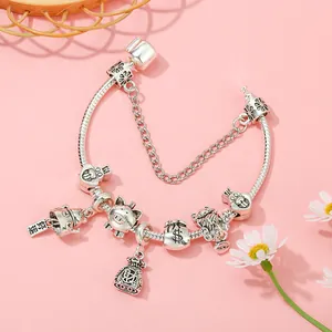 Silbernes Charm-Armband mit Glückskatze und Geldsack-Anhängern auf rosa Hintergrund