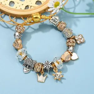 Golden snake chain bracelet with heart, crown and star charms on a light blue background