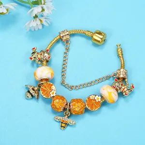 Golden charm bracelet with lucky cat, bee pendants and orange beads on snake chain