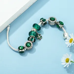Silver snake chain bracelet with deep green emerald beads and a lucky clover pendant