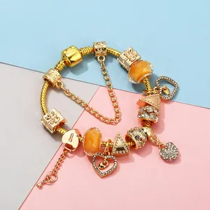 Golden Pandora style bracelet with heart charms and orange beads on geometric background