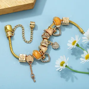 Golden snake chain bracelet with heart lock and key charms on light blue background