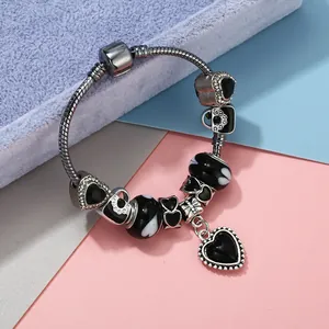 Détails d'un bracelet maille serpent argenté avec des breloques en émail cœur noir
