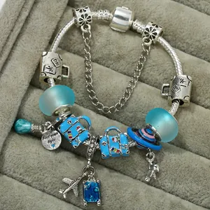 Detailed shot of silver charm bracelet featuring blue enamel suitcases and travel charms