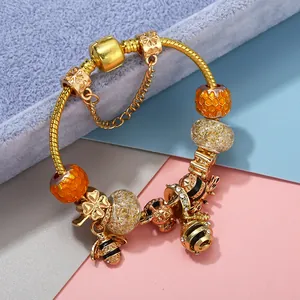 Golden bee charm bracelet with clover pendant and honey-colored beads on blue velvet