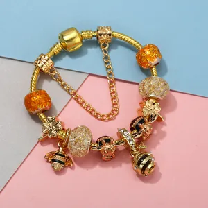 Golden snake chain bracelet with bee pendants and honeycomb beads on geometric background